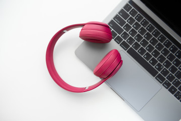 Flay lay of pink wireless headphone on the laptop keyboard