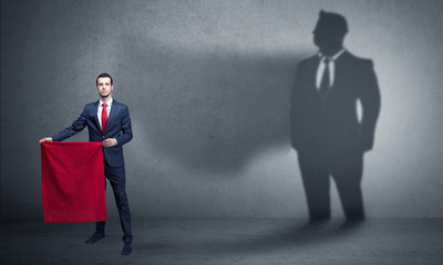 Businessman standing with red cloth on his hand and his shadow on the background
