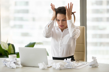 Stressed businesswoman feel despair sitting at desk with crumpled papers, unable to finish work or...