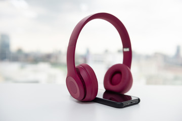 Obraz na płótnie Canvas Pink wireless headphone and smart phone on the white table