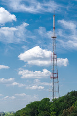TV tower on a background of blue sky and green trees