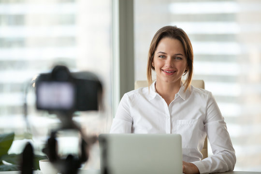 Successful businesswoman smiling recording video for online business course, confident female coach talking and sharing experience, making vlog for users or students, vlogger shoot training on camera