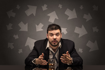 Drunk disappointed man sitting at table with arrows around
