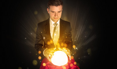 Gorgeous businessman sitting with sparkling magic ball in his lap
