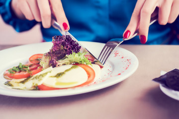 Woman in blue dress eating green healthy tasty eco salad on city street cafe.