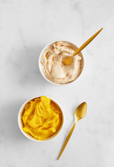 Mango and hazelnut ice cream in a cups viewed from above on a marble background. Top view