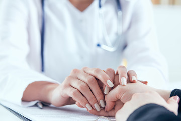Friendly female doctor's hands holding female patient's hand for encouragement and empathy close-up. Partnership, trust and medical ethics concept.