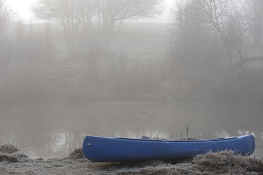 Blue Cannoe in a Foggy Morning