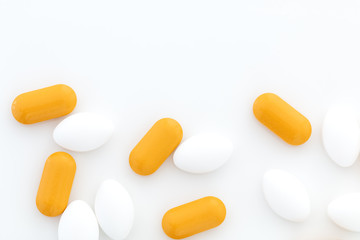 Yellow and white pills on white background, place for text.