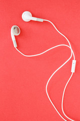 earbuds or earphones on red background