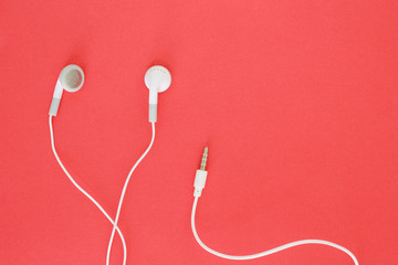 earbuds or earphones on red background