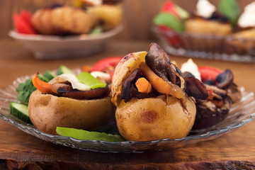 Oven-cooked eggplant and potatoes stuffed with butter-fried sliced mushrooms with onions and carrots, decorated with slices of cucumbers, tomatoes and white soft cheese.