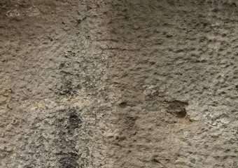 The fragment of the old wall is covered with beige street plaster and black paint.