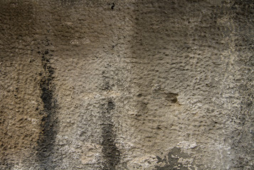 The fragment of the old wall is covered with beige street plaster and black paint.
