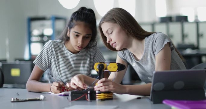 High school students working on a robotic arm in class