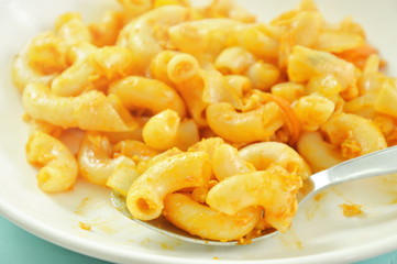 stir fried macaroni and egg with ketchup scooping in silver spoon on plate