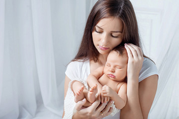 Obraz na płótnie Canvas Pretty woman holding a newborn baby in her arms
