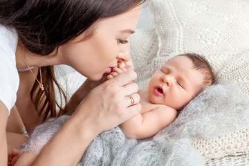 Pretty woman holding a newborn baby in her arms. Happy mother and her slipping newborn baby in the bed