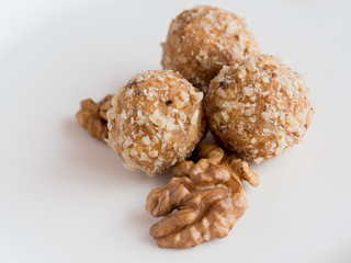 Homemade walnut balls on a white plate with walnuts, traditional Christmas sweets close up