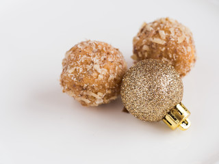 Homemade walnut balls on a white plate with flashy red christmas ornament