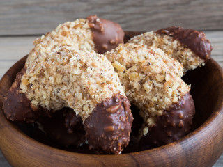 Homemade walnut rolls with dark chocolate in a wooden bowl, traditional Christmas sweets