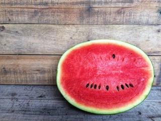 A slice half of fresh watermelon on a wooden table.