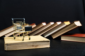 Stack of old books on a wooden shelf and shopping carts