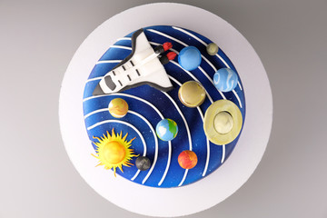 Cake with the image of the cosmos drawn by airbrush. Galaxy, stars, solar system with planets and spaceship. Picture for a menu or a confectionery catalog. Top view.