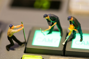 Miniature people : worker on Switcher buttons in studio TV station, Audio and Video Production...