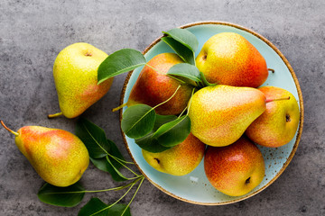 Fresh bio pear with leaves on the plate. Gray stone table.