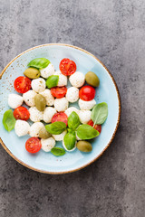 Delicious caprese salad with ripe cherry tomatoes and mini mozzarella cheese balls with fresh basil leaves.