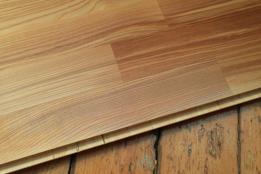 An image of an old wooden floor and a new parquet board.