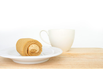 chocolate cake roll on white plate and cup coffee on wooden mat.