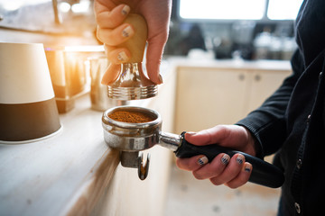 Barista presses ground coffee using tamper.