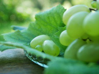 Polonne / Ukraine - 02 August 2018: Green grapes fruits with leaves in the basket on rustic wood background