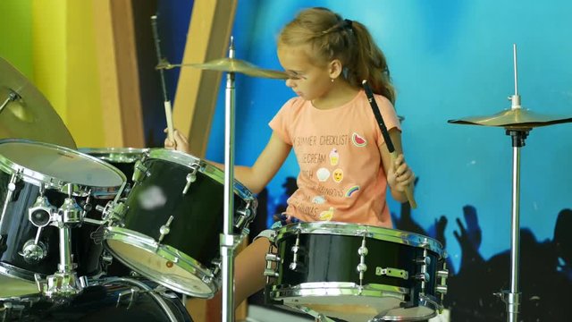 Young girl playing drums. Inept attempts to play the drums.
