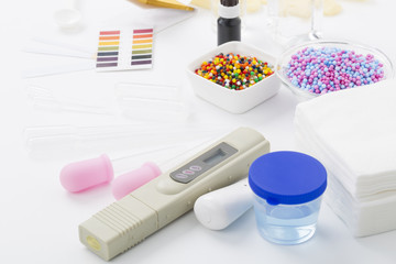 Cosmetic ingredients safety testing tools, pH value, water powder value, moisture degree, pH test paper, dropper, chemical solvent, and rubber gloves in white background