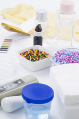 Cosmetic ingredients safety testing tools, pH value, water powder value, moisture degree, pH test paper, dropper, chemical solvent, and rubber gloves in white background