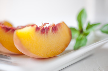 Fototapeta na wymiar Slices of peach served on a white plate