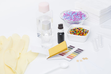 Cosmetic ingredients safety testing tools, pH value, water powder value, moisture degree, pH test paper, dropper, chemical solvent, and rubber gloves in white background