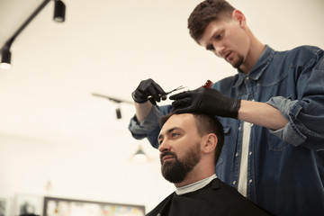 Professional barber working with client in hairdressing salon. Hipster fashion