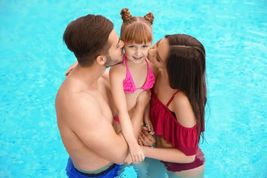 Parents kissing their daughter in swimming pool