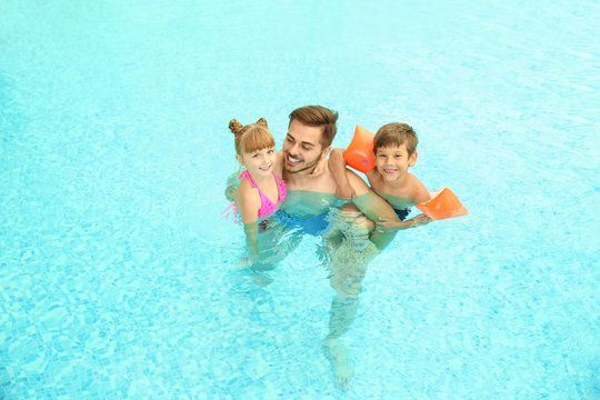 Happy father with children in swimming pool