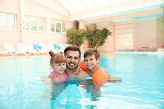 Happy father with children in swimming pool