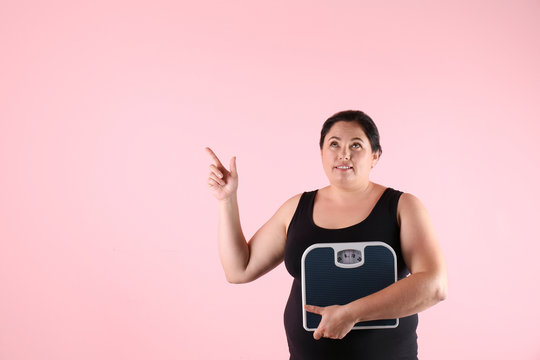 Overweight woman in sportswear with scales on color background