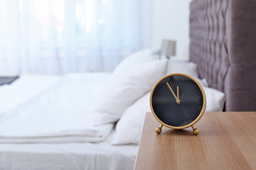 Stylish alarm clock on bedside table. Time to wake up - obrazy, fototapety, plakaty