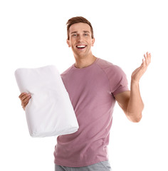 Young man in pajamas with pillow on white background