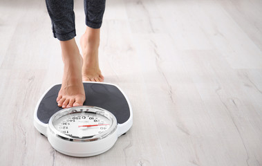 Woman measuring her weight using scales on floor - Powered by Adobe