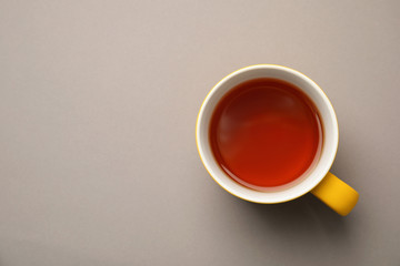 Cup of black tea on color background, top view