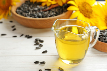 Jug of sunflower oil and seeds on table